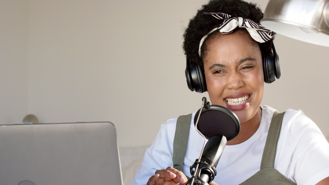 mujer afroamericana haciendo podcast con un micrófono en casa