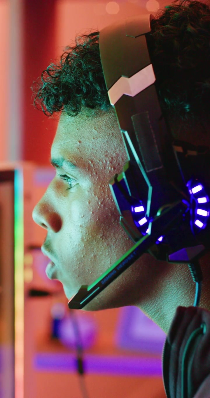 Giovane giocatore con cuffie che gioca a un videogioco in una stanza illuminata al neon