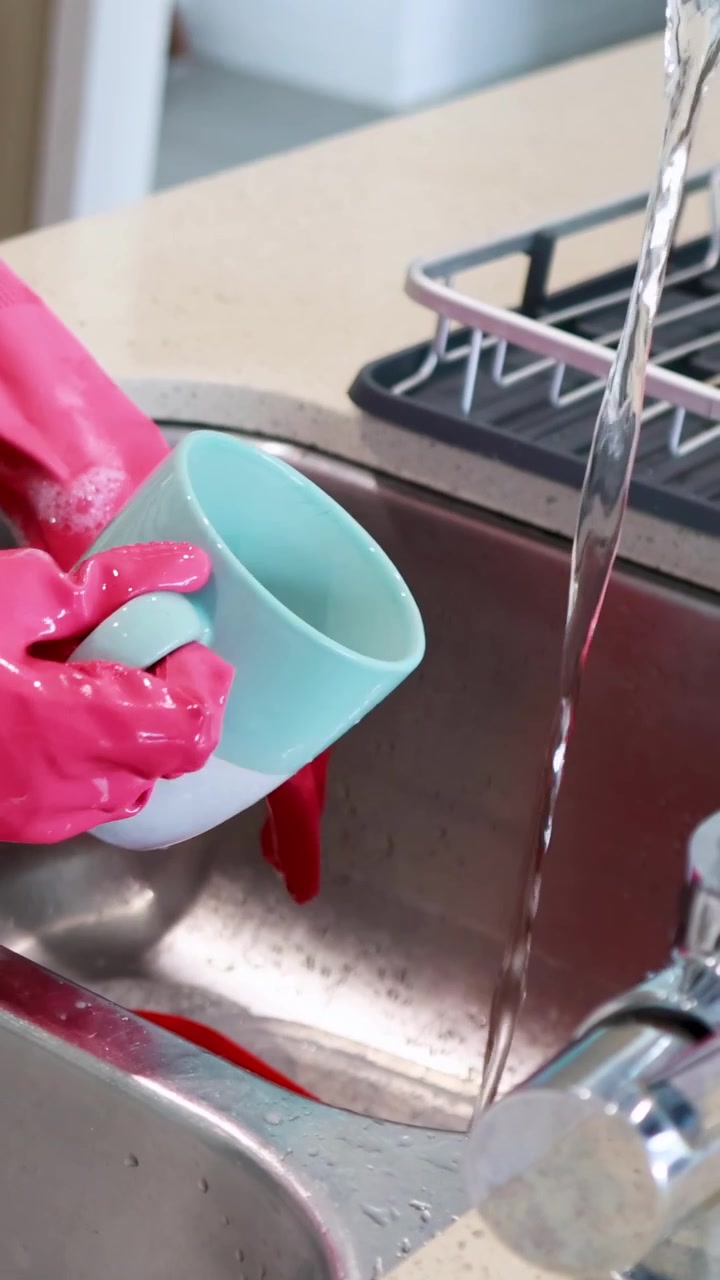 Persona che lava una tazza di ceramica nel lavello della cucina
