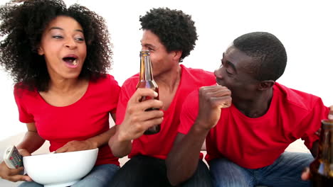 Football-fans-in-red-sitting-on-couch-cheering