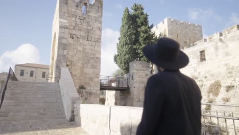 a man in traditional attire is gazing thoughtfully at ancient stone structures under soft daylight