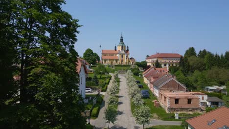 Gasse-Mit-Weiß-Blühenden-Bäumen,-Wunderbare-Luftaufnahme-Der-Flugkirche-Auf-Einem-Hügel-Im-Dorf-Chlum-In-Der-Tschechischen-Republik,-Europa,-Sommertag-2023