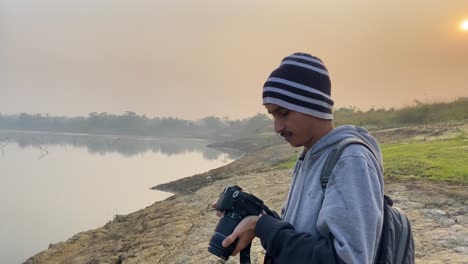 closeup portrait of young man taking photographs of polluted river, hazy morning