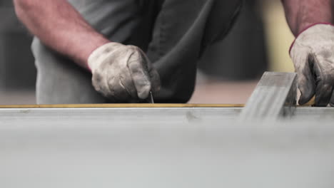 worker marking measurements on metal tubular frame - close up, slow motion