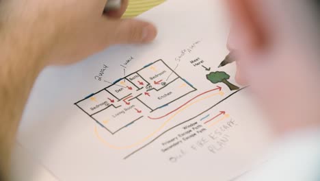 Fire Prevention Officer creating a home escape plan on paper (Close Up)