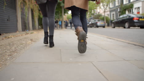 close up of couple's feet walking along city street