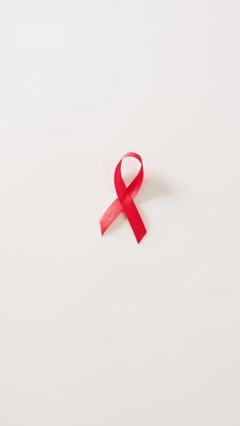 vertical video of red hiv or aids awareness ribbon on white background with copy space