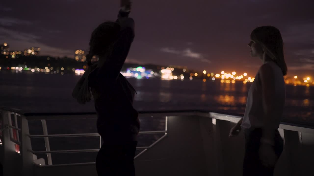 силуэт двух красивых молодых женщин, танцующих на палубе корабля ночью. подруги на лодке