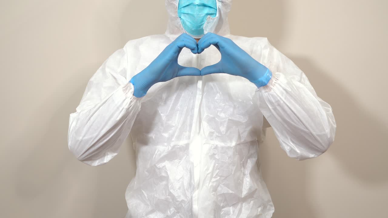 doctor in ppe suit making heart gesture with hands