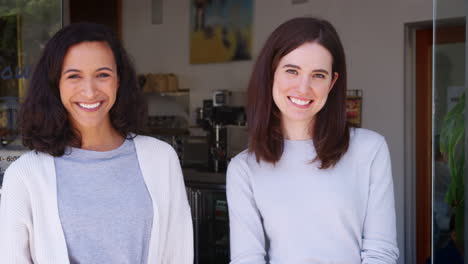 two female friends standing in a coffee shop, smiling