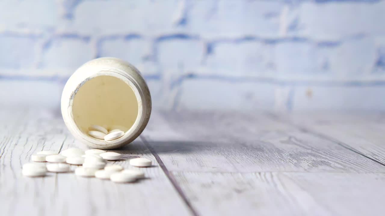 pastillas blancas en un frasco viejo en una mesa de madera