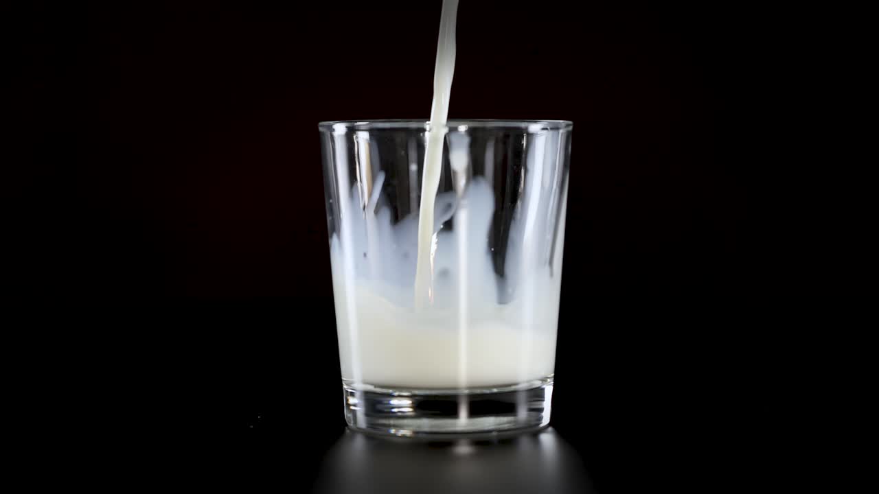 la leche se vierte en un vaso transparente