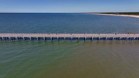 Drone-Ver-Un-Puente-De-Pie-En-La-Playa-De-Palanga,-Que-Va-Al-Mar-Báltico