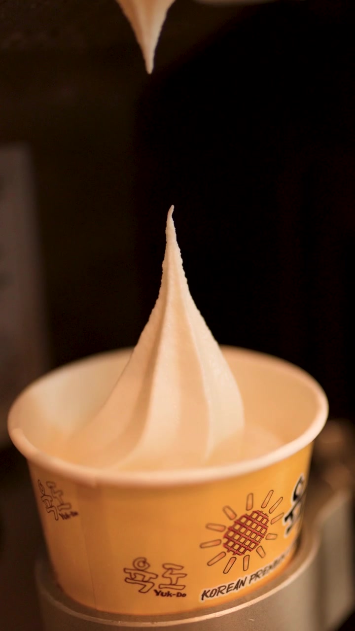 Primo piano di una macchina che eroga gelato soft alla vaniglia in un bicchiere di carta