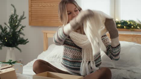 mujer caucásica abriendo y probando regalos de navidad en su dormitorio