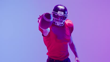 video of caucasian american football player in helmet with ball over neon purple background