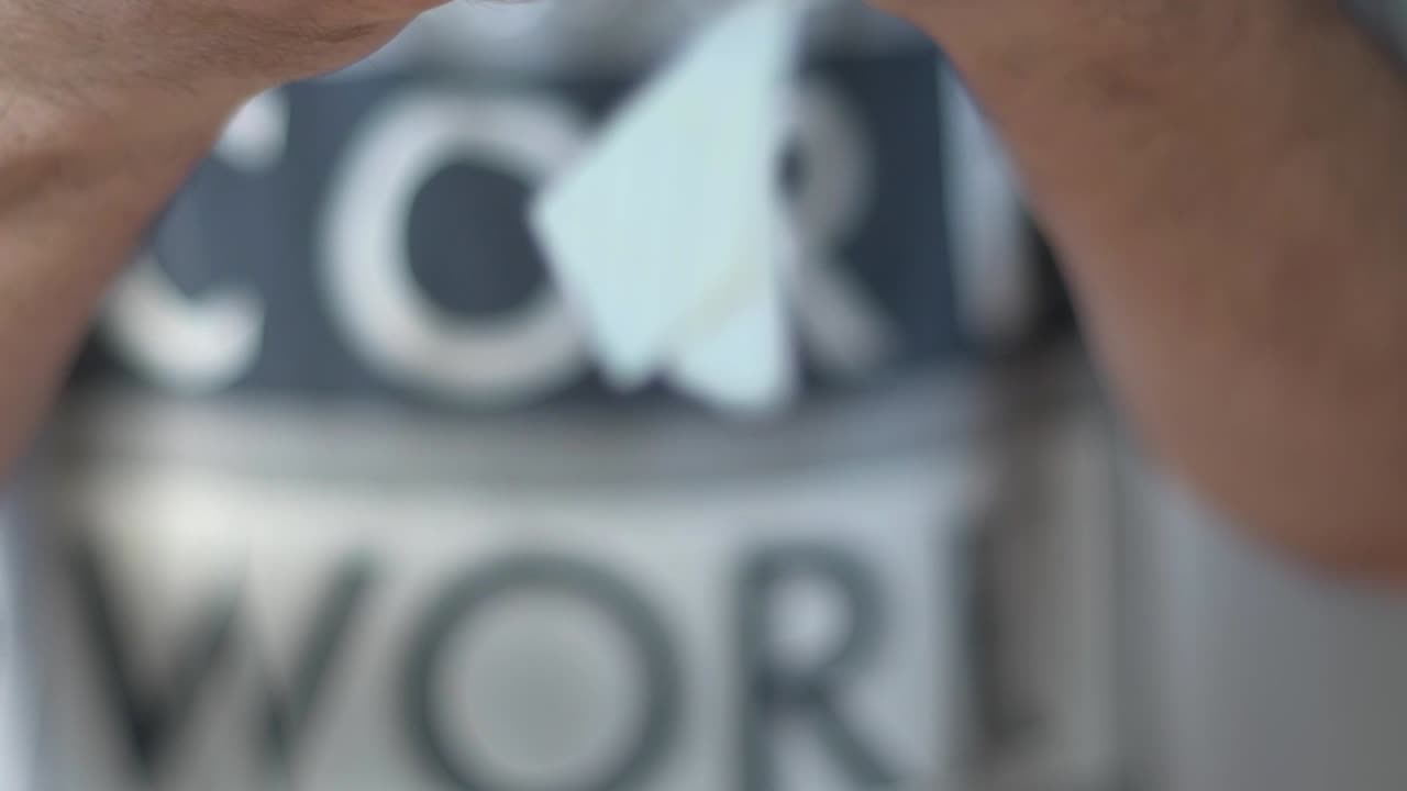 Man's hand tearing paper with a drawn heart into small pieces.