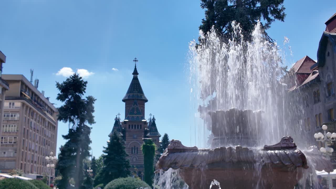 Scenic view highlighting the cathedral and active fountain in Timisoara, emphasizing architecture, water features, and urban charm