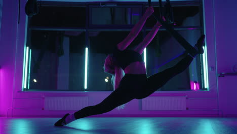 mujer está haciendo split en clase de yoga aérea usando hamaca para estirar las piernas elegante mujer deportiva