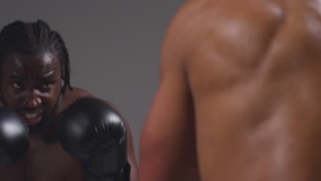 Close-Up-Studio-Shot-Of-Two-Male-Boxers-Wearing-Gloves-Fighting-In-Boxing-Match-Against-Grey-Background-7