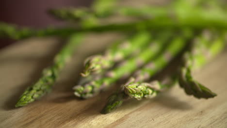 slow motion footage of a bunch of fresh, green asparagus falling on to a wood cutting board