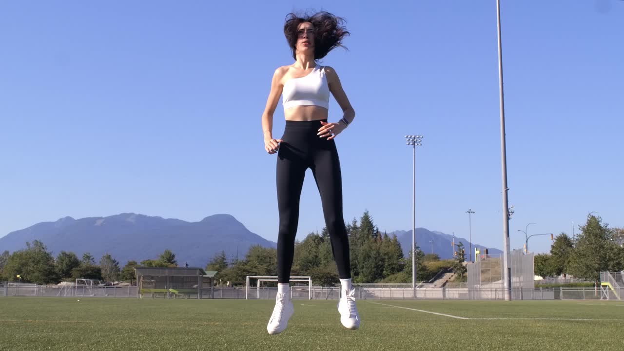 Fit Woman Exercises at Sports Field - Jump Squat Slomo - Sunny Day