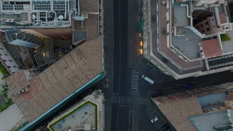 Top-down-view-of-buildings-along-street-in-city-at-twilight.-Low-traffic-passing-through-road-intersection.-Rome,-Italy