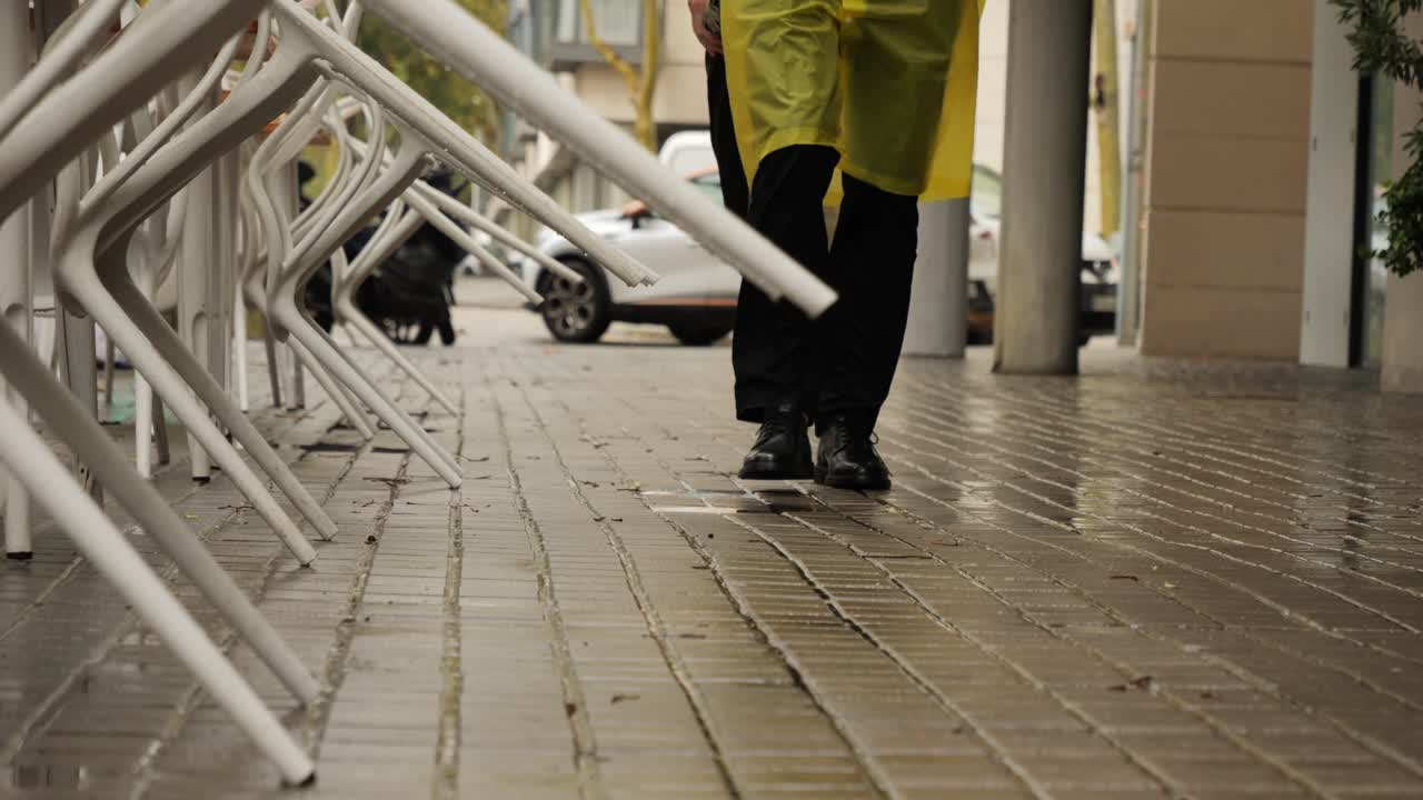 Business man tourist person with umbrella and raincoat on rainy european city street, lights reflecting, walking in Barcelona or Amsterdam during the rain