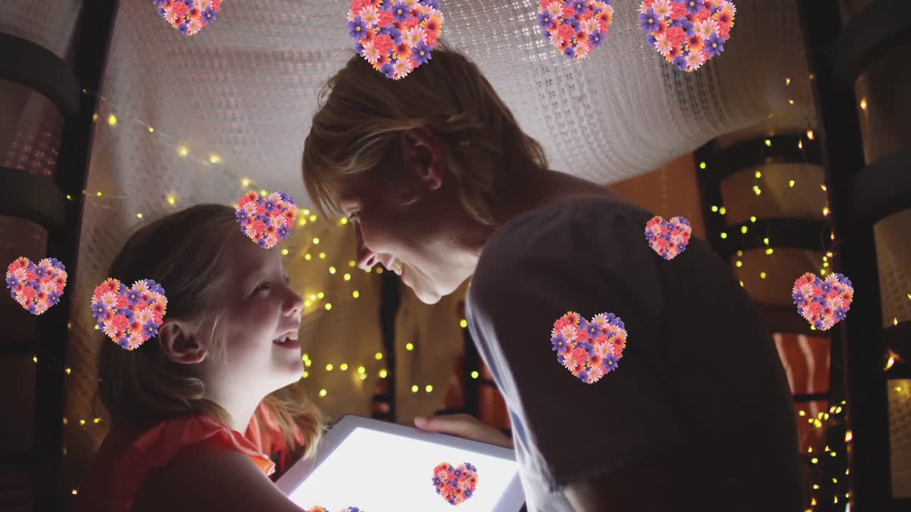 임시 텐트에서 태블릿을 사용하는 행복한 백인 어머니와 딸 위의 꽃 마음의 애니메이션