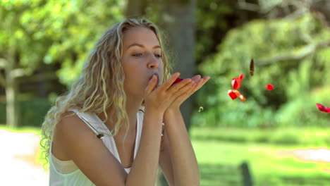 blonde woman blowing in slow motion on petals