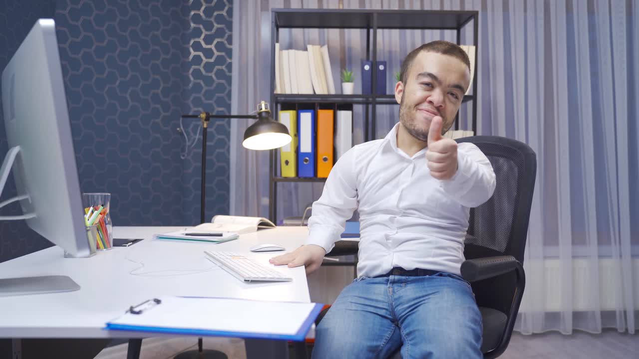Disabled midget man sitting in his office looks at the camera and makes an OK sign.