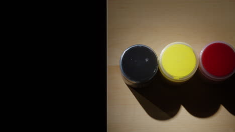 colorful paint containers on wooden surface