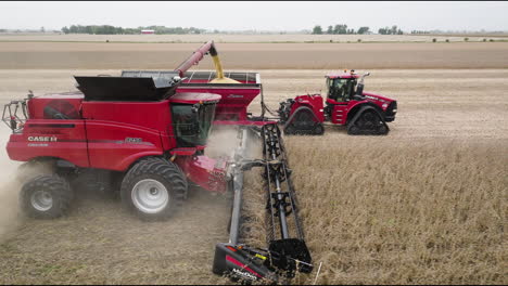 aerial view of combine harvester transferring soybean grains to tractor-attached grain cart