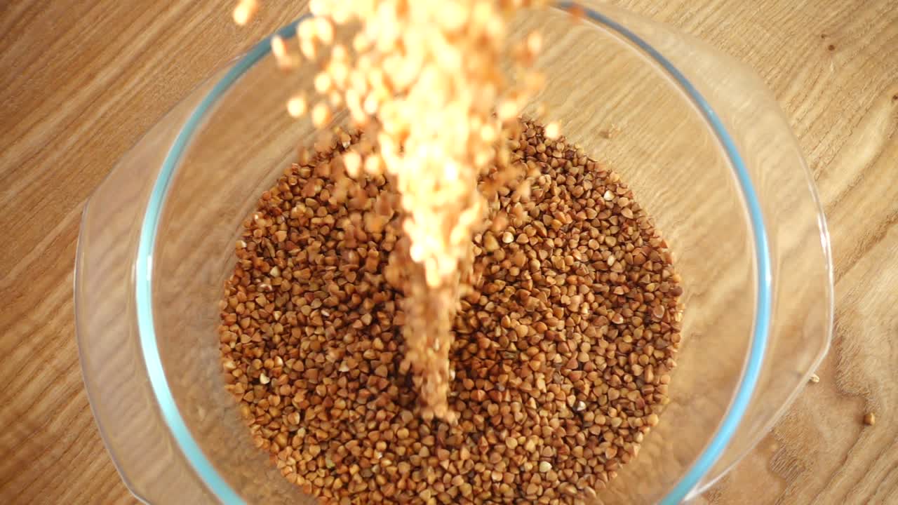 Buchweizen wird in eine Glasschale gegossen. Zeitlupe