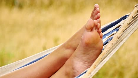 Close-up-Footage-of-a-Person's-Feet-Resting-in-a-Hammock,-in-a-Green-Field