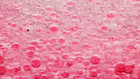 macro shot of red bubbles in water moving right with yellow background