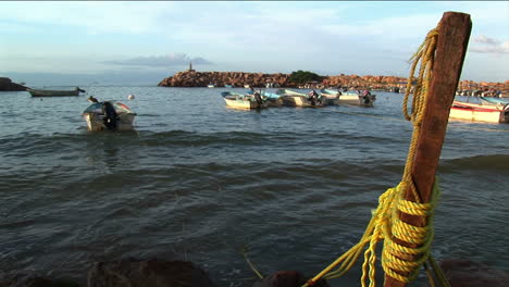 Un-Bote-A-Motor-Atado-A-Un-Poste-De-Muelle-Rocas-En-Las-Olas