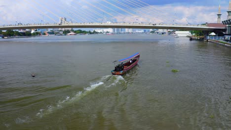 chao phraya river with thai longtail boat crossing under rama viii bridge in bangkok, thailand