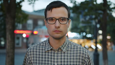 man in glasses on city street at dusk