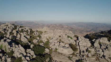 Drone-Aéreo-En-Movimiento-Hacia-Atrás-Sobre-Impresionantes-Cimas-De-Montañas-Rocosas-En-El-Torcal-De-Antequera,-Rocas-Karstik,-España-Al-Atardecer