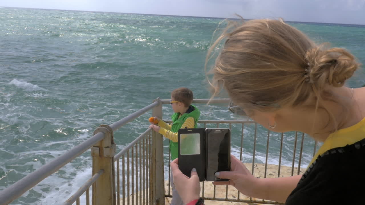 madre tomando una foto celular de un niño mirando al mar rosh hanikra