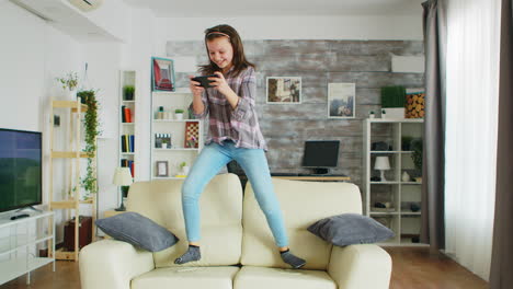 Niña-Saltando-En-El-Sofá-De-La-Sala-De-Estar