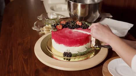 woman cutting a beautiful multi-layered cake with fresh berries