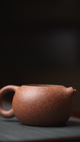 woman's hand placing lid on small brown ceramic teapot