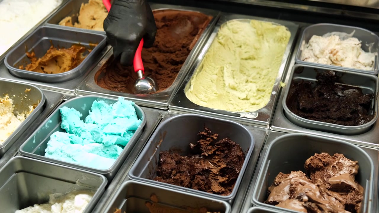Mano che serve gelato al cioccolato da una vetrina assortita