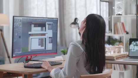 ingeniera asiática con dolor de espalda mientras diseña una casa en un escritorio en casa. juegos cibernéticos diseño y decoración de casas