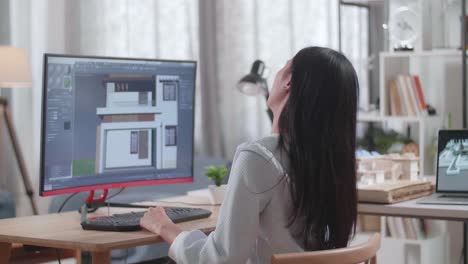 asian woman engineer having a backache while designing house on a desktop at home. cyber games house design and decoration