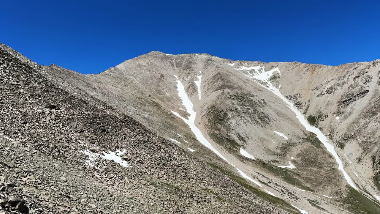 Hiking summit Mt Mount Princeton hiking trail 14er spring summertime Buena Vista Salida Colorado Sawatch Range melting snow fields Rocky Mountains blue clear sky morning windy breeze pan left