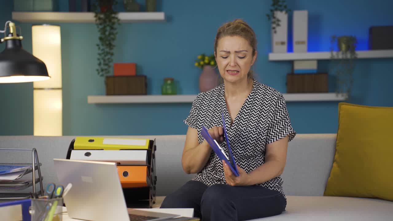 una trabajadora de oficina en casa mirando el archivo con enojo.