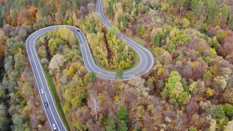 cars on modern country roadway, remote route in fall foliage woodland aerial panorama